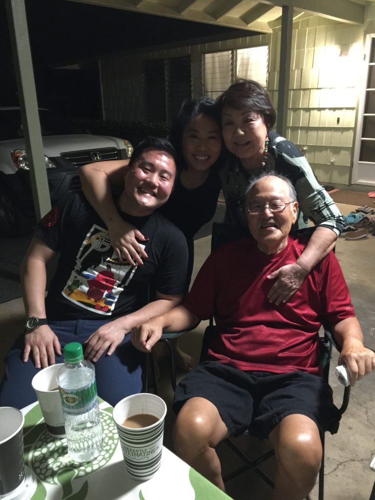 Photo of Reid with three members of his family smiling and relaxing in front of a home